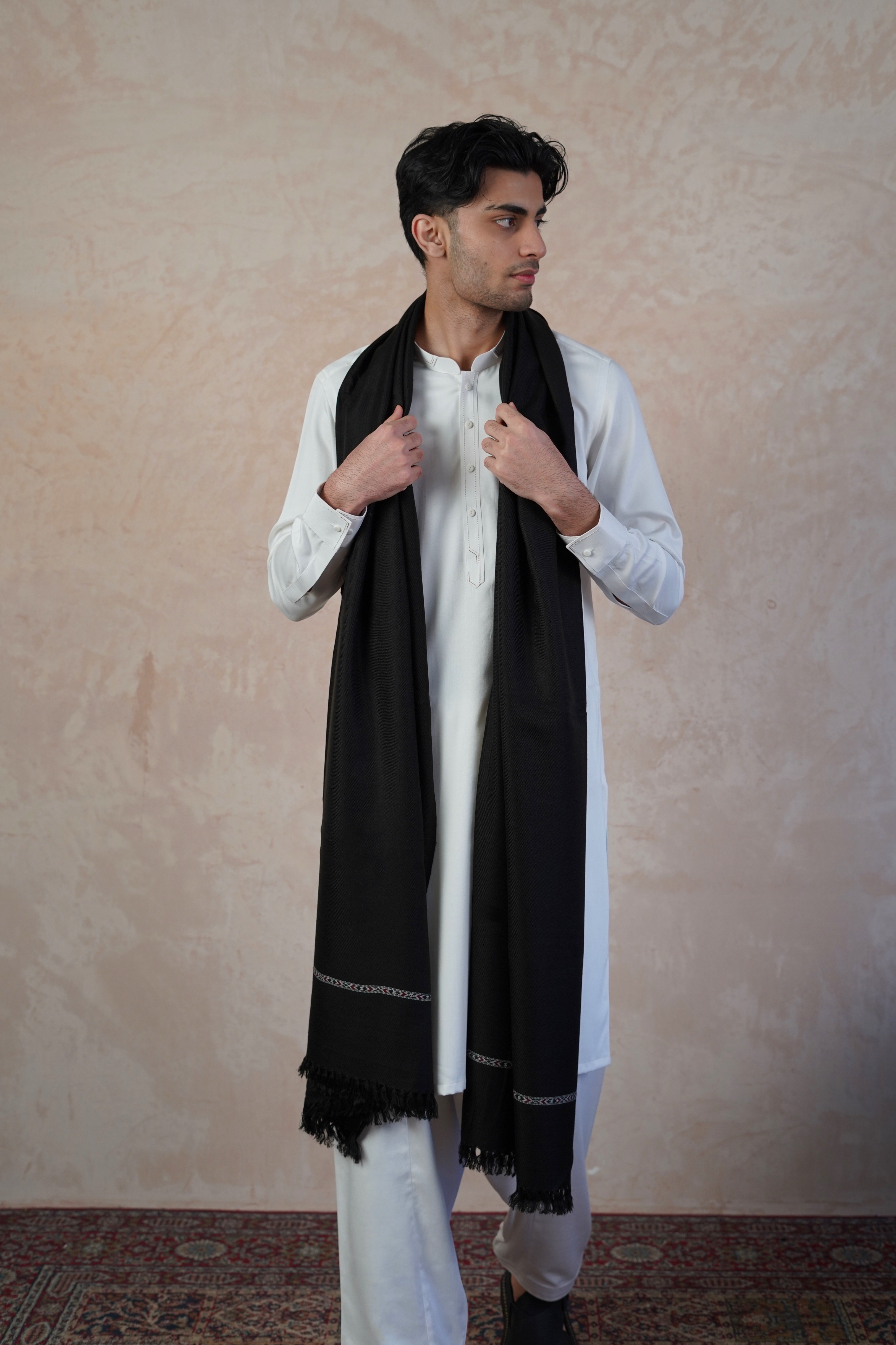 Pakistani male model wearing UD Fabrics white shalwar kameez and Black shawl