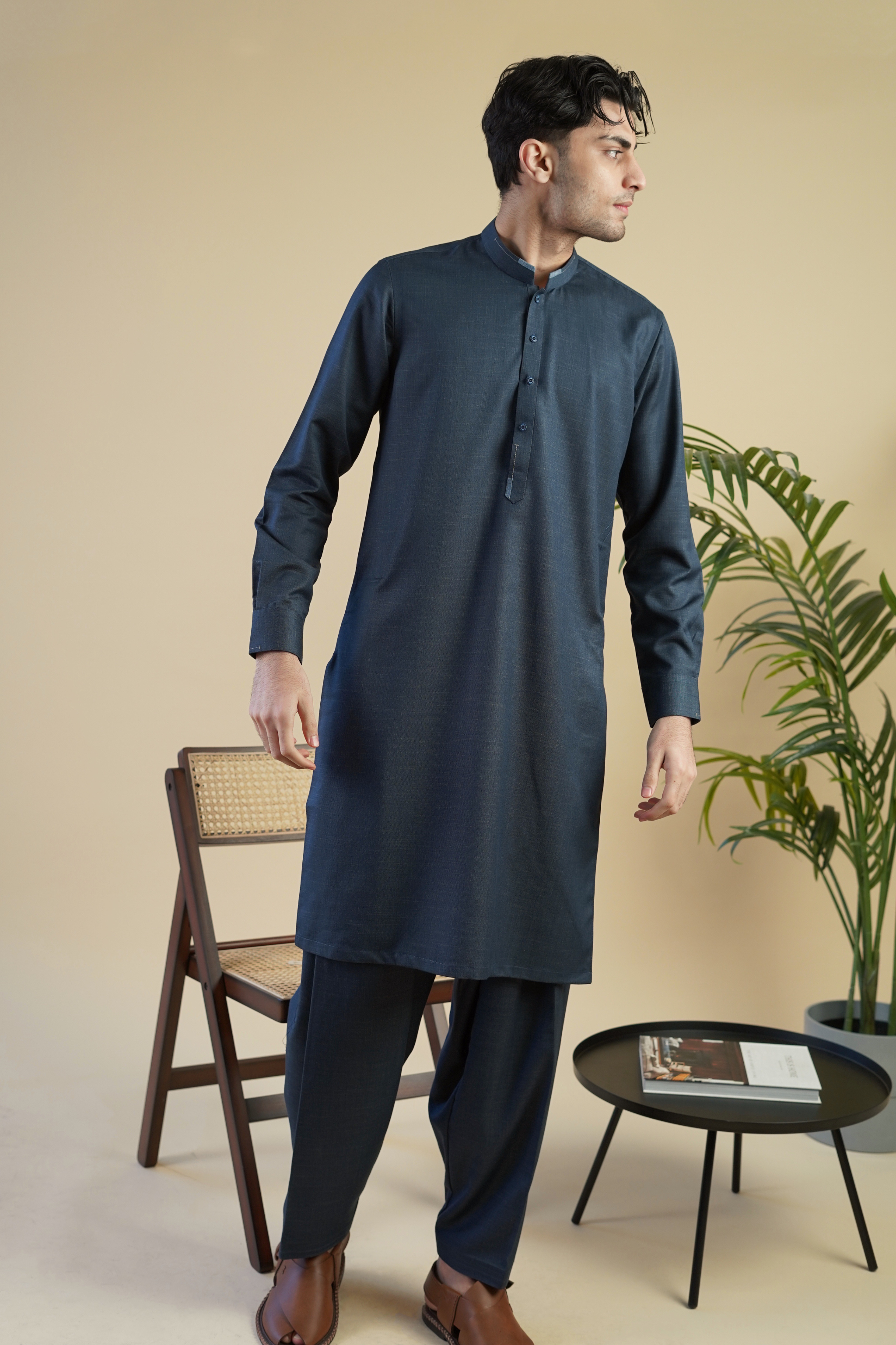 Pakistani male model wearing a UD Fabrics deep aqua blue shalwar kameez with lighter blue design on the collar