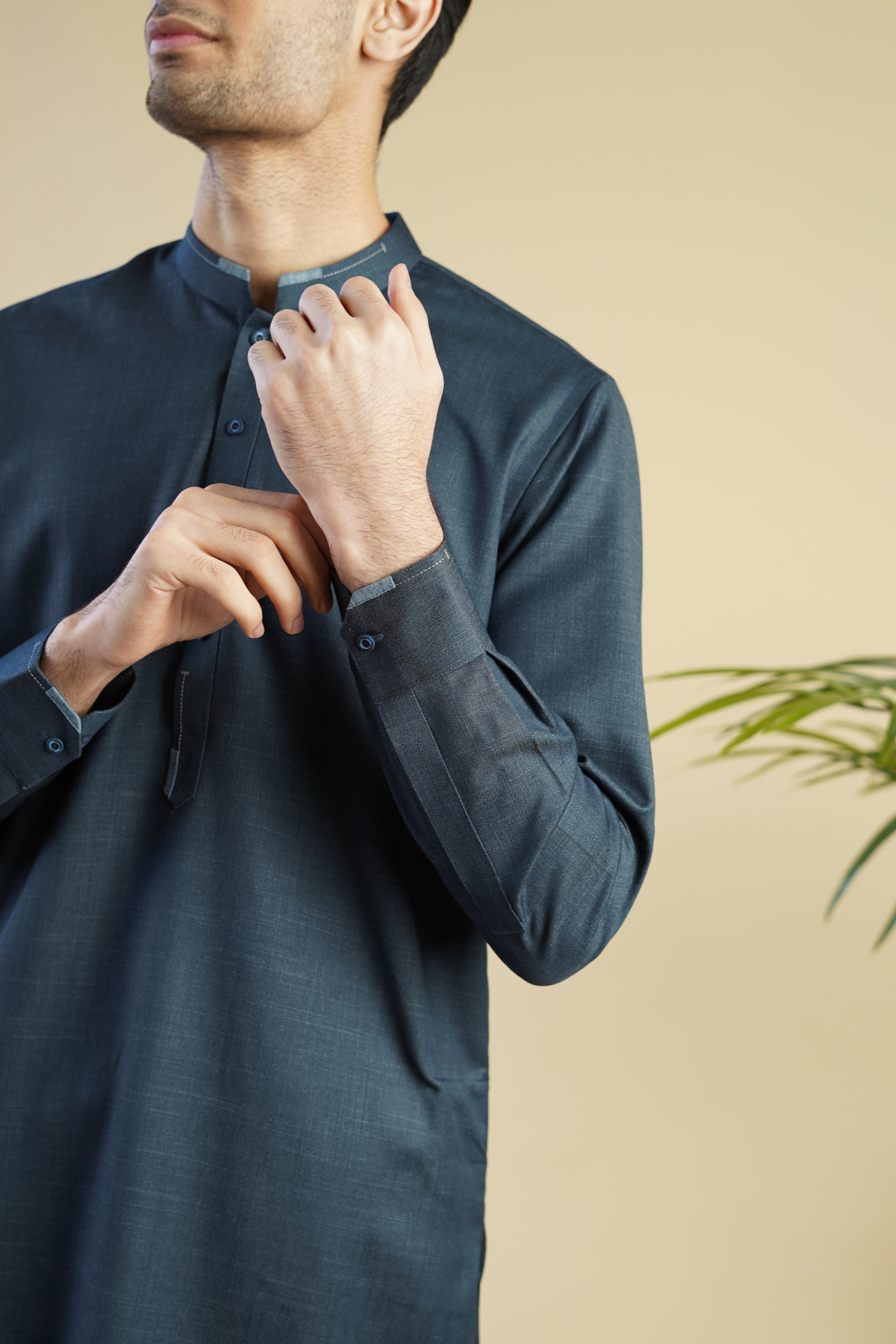 Detail close up image of Pakistani male model wearing a UD Fabrics deep aqua blue shalwar kameez with lighter blue design on the collar