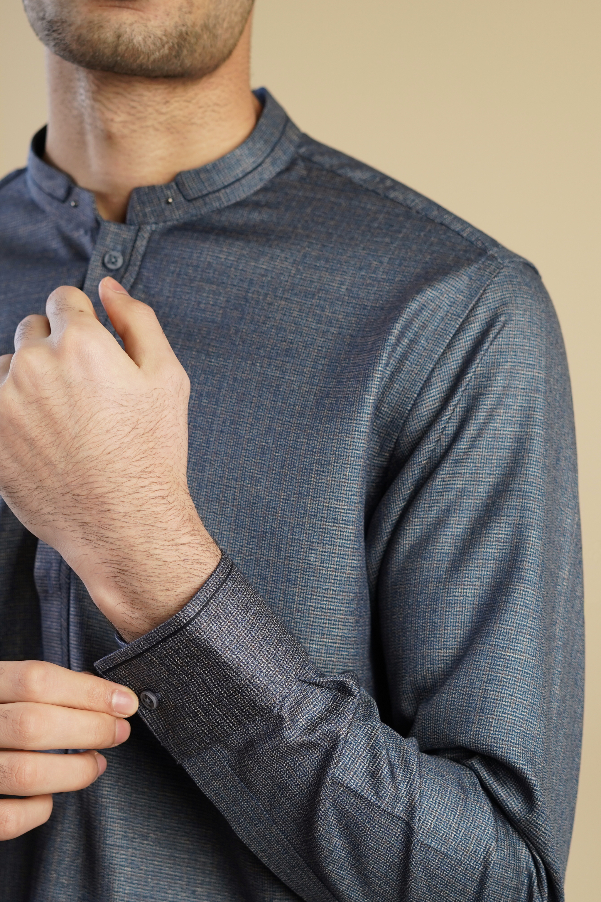 Detail close up image of Pakistani male model standing wearing UD Fabrics men's grey shalwar kameez. Shalwar kameez with design on collar. Model poses looking away from camera. Men's pakistani clothing