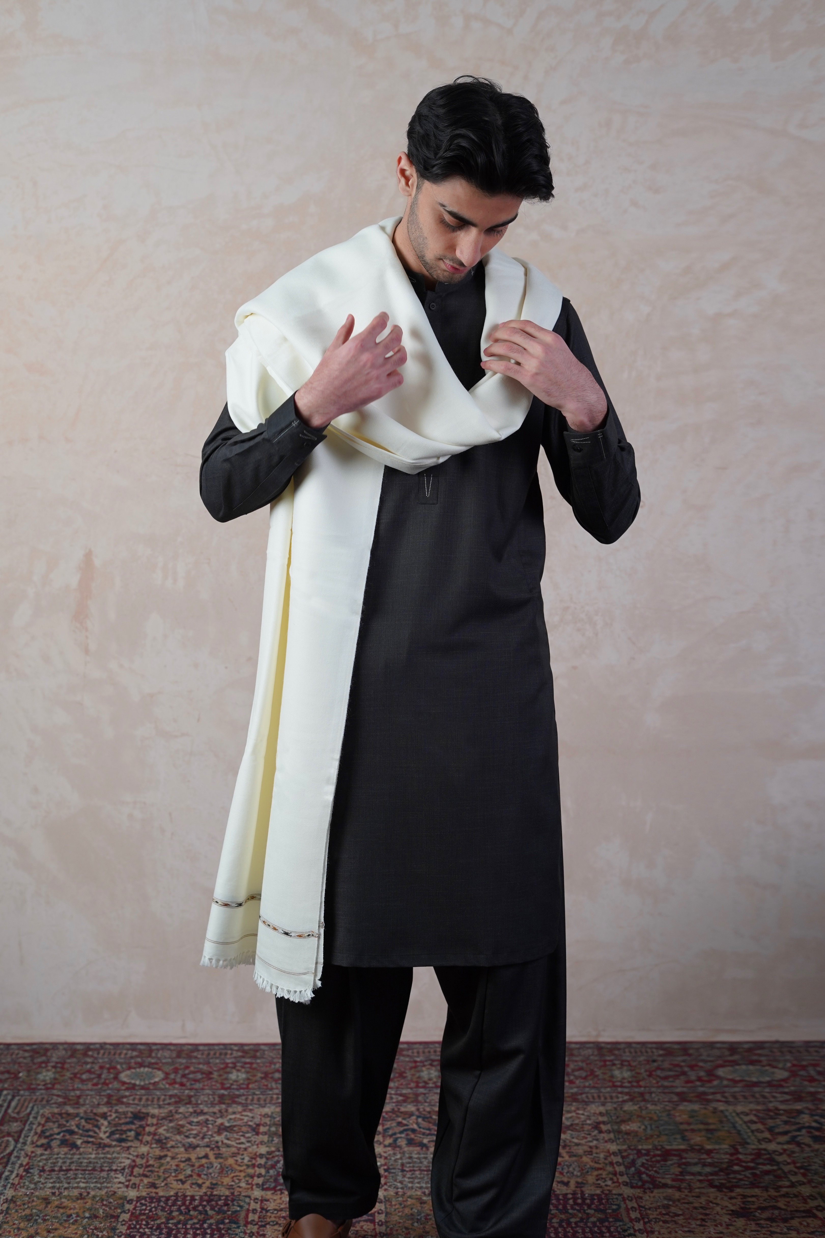 Pakistani male model wearing UD Fabrics black shalwar kameez and off white shawl