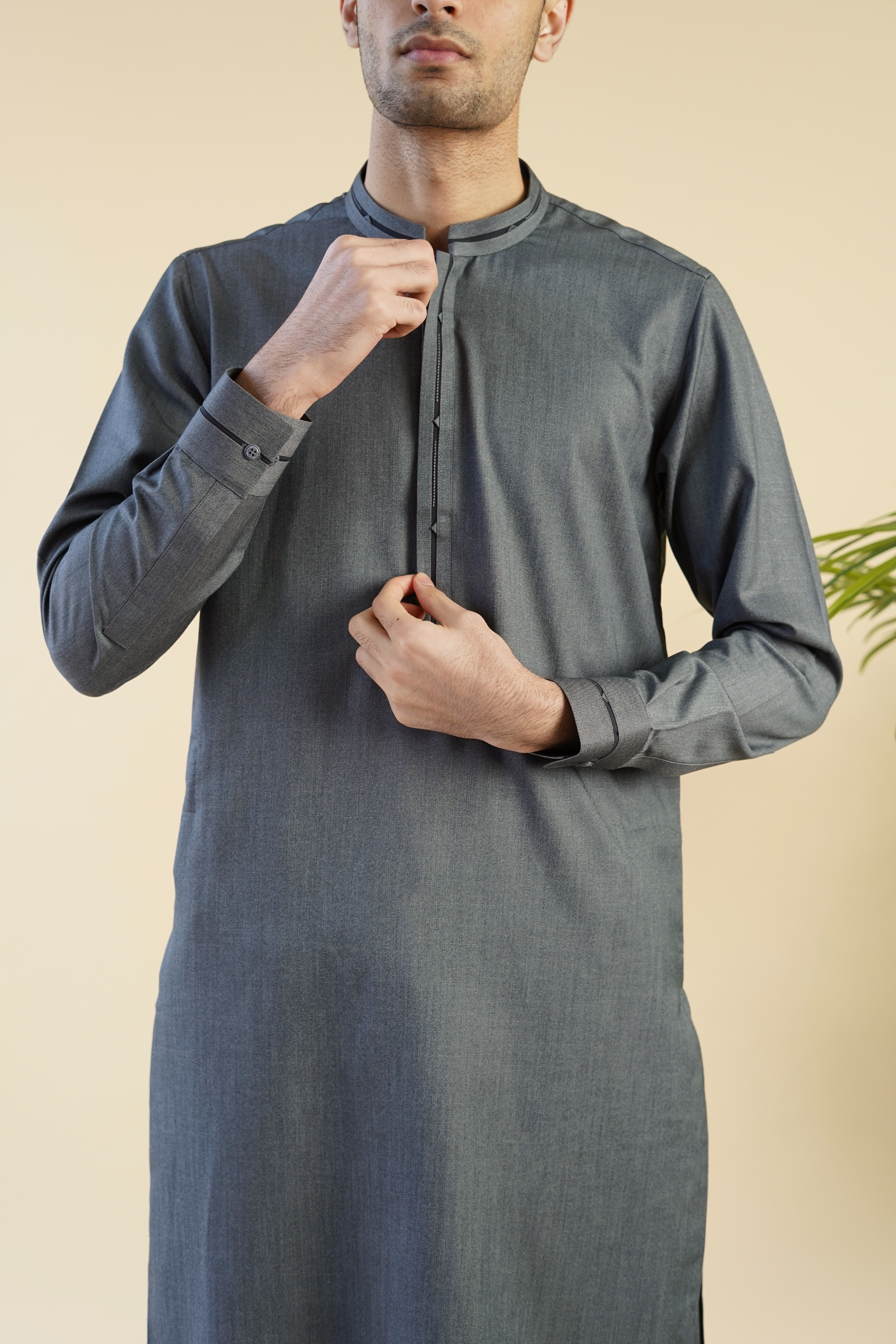 Detail image of Pakistani male model wearing UD Fabrics shalwar kameez in grey with black band design on collar.