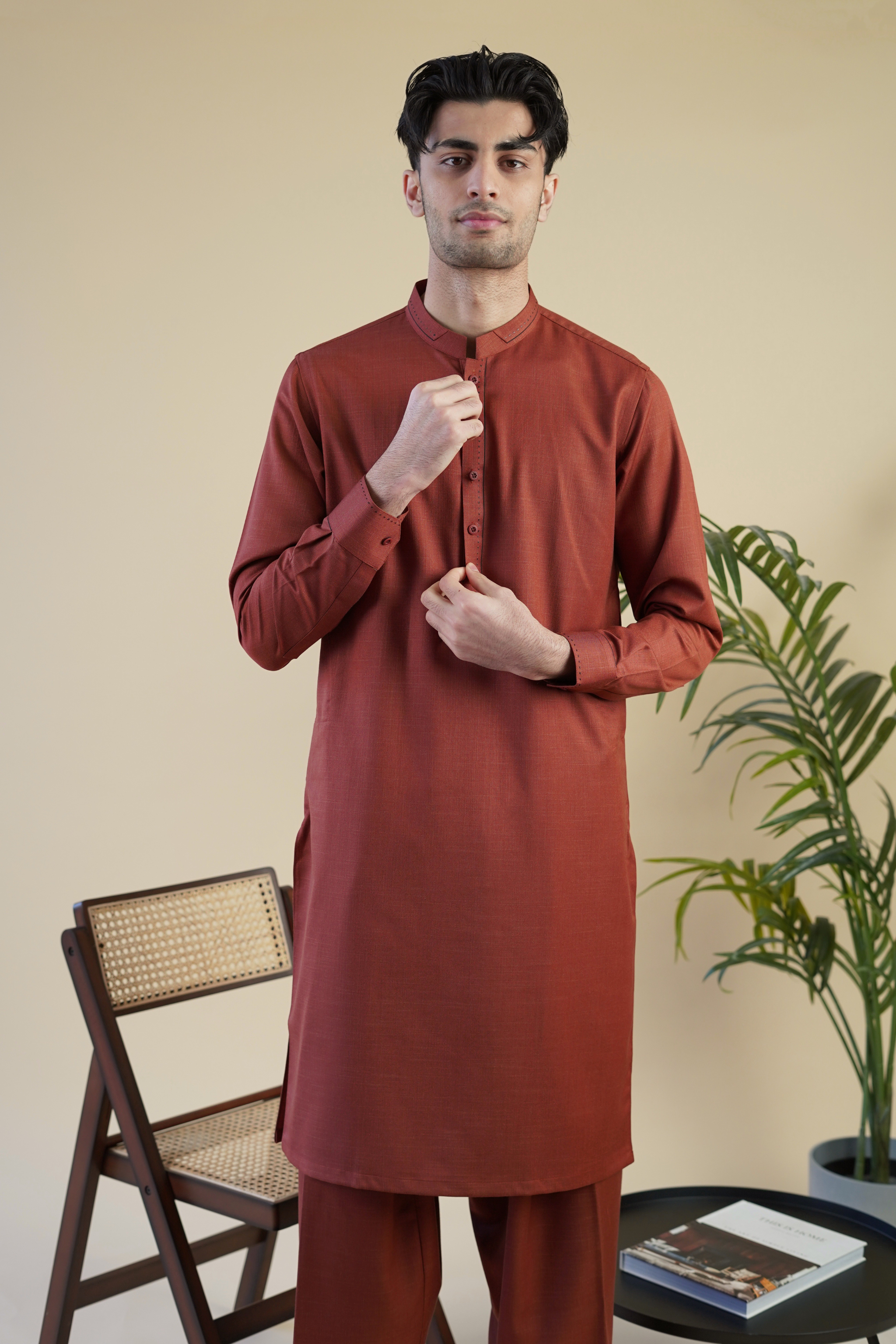 Detail image of Pakistani male model wearing UD Fabrics men's red shalwar kameez with design on collar.