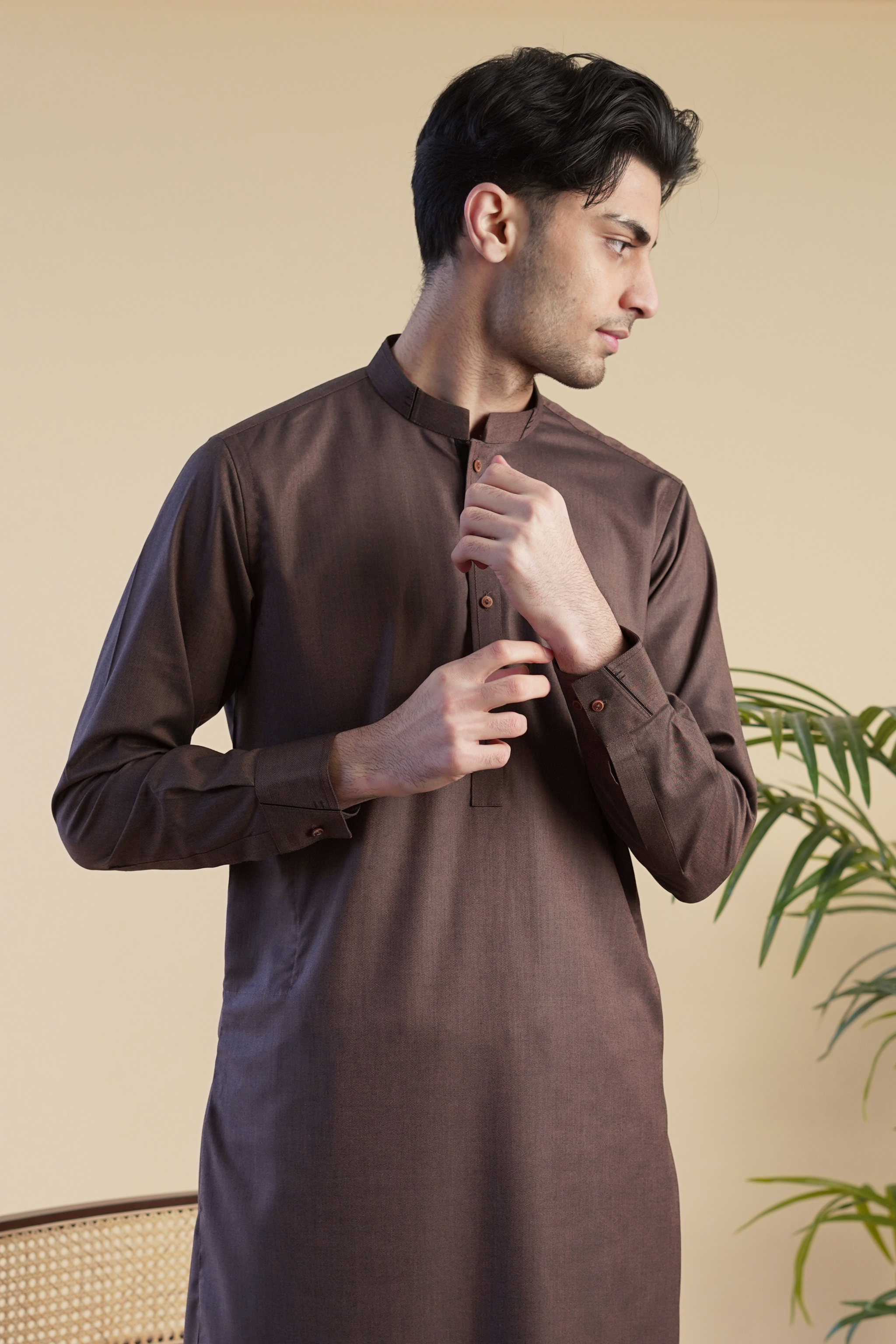 Detail image of Pakistani male model wearing UD Fabrics men's brown shalwar kameez . Model poses looking away from camera